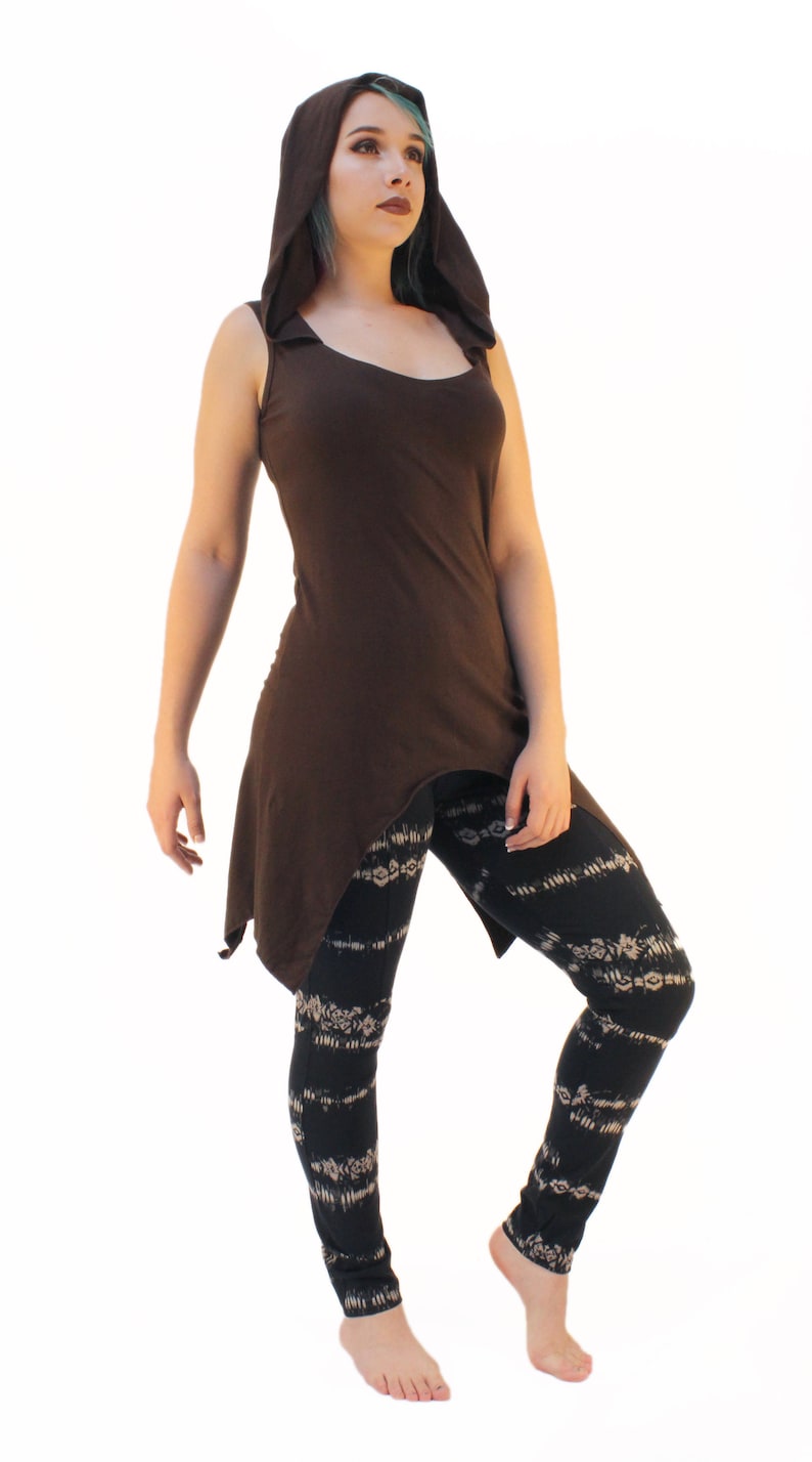 May include: A brown sleeveless hooded top with a high low hemline. The model is wearing black leggings with a white floral pattern.