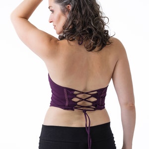 May include: A purple halter top with a lace-up back. The top is made of a soft, stretchy fabric and has a relaxed fit.
