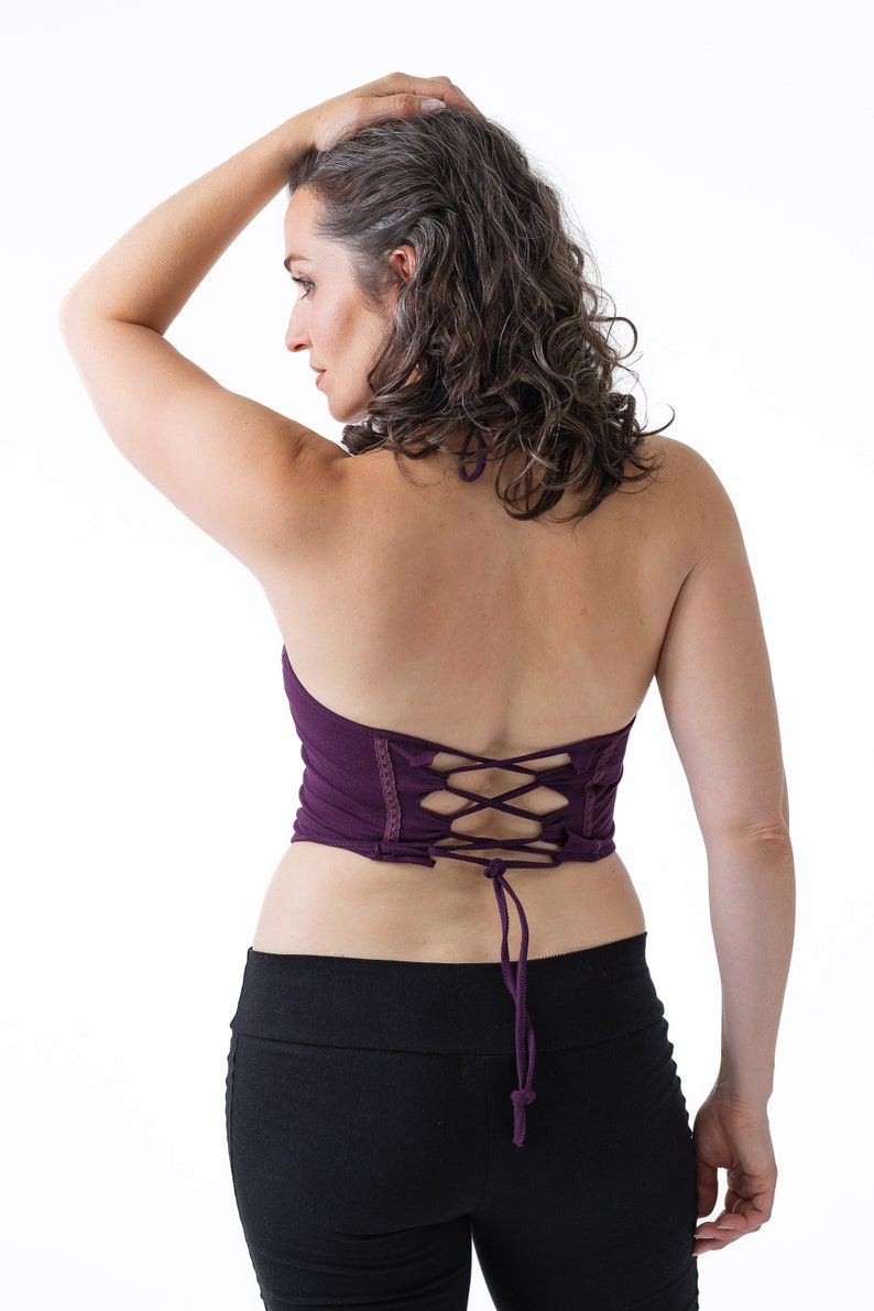 May include: A purple halter top with a lace-up back. The top is made of a soft, stretchy fabric and has a relaxed fit.
