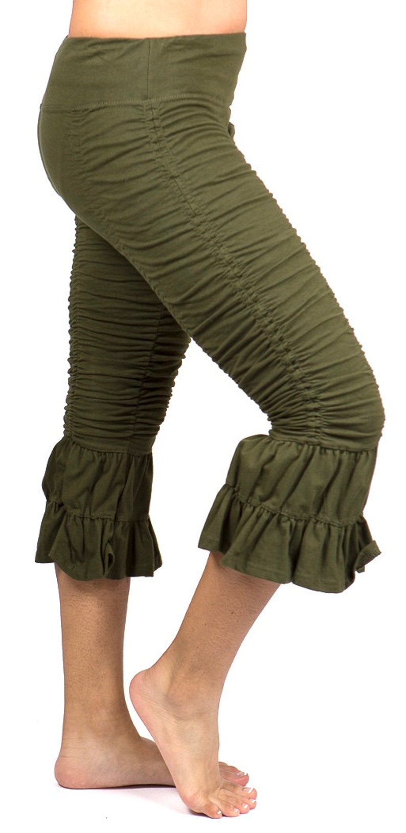 May include: Olive green capri leggings with a ruffled hem. The leggings are made of a soft, stretchy fabric and have a comfortable fit.
