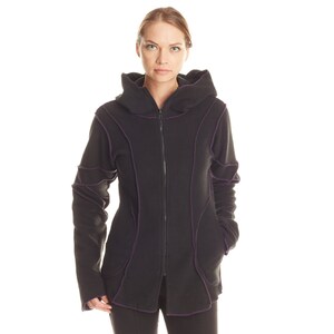 May include: A black zip-up hooded jacket featuring prominent purple exposed seams and paneling. The jacket includes a full-length front zipper, a hood, and long sleeves with visible stitching details that follow the contours of the garment.