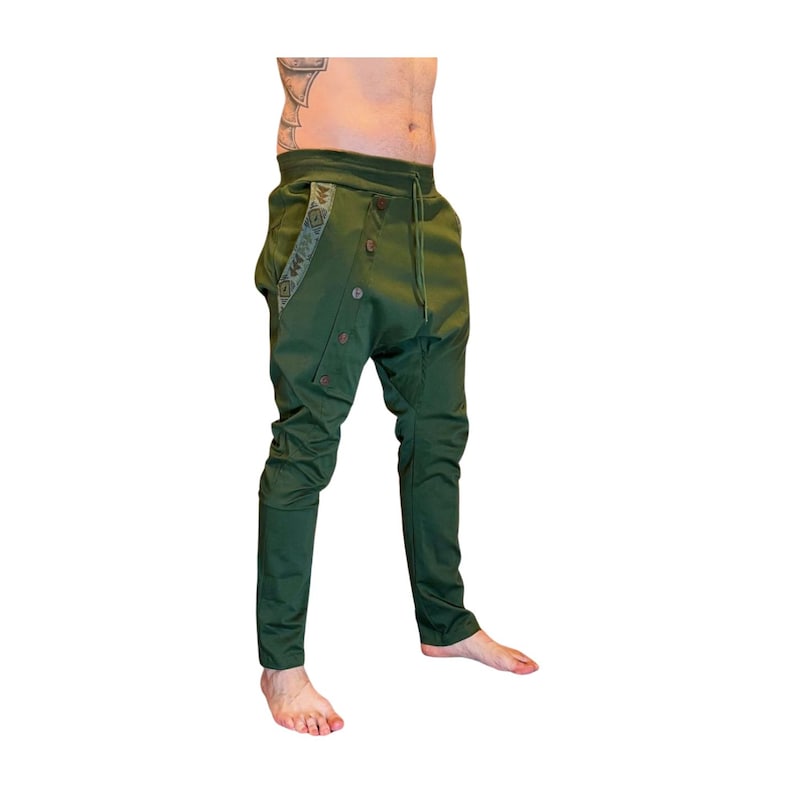 Puede incluir: Pantalones verdes con un dise&ntilde;o &uacute;nico. Los pantalones tienen cierre de botones, cintura con cord&oacute;n y adornos decorativos en el bolsillo. Los pantalones tienen un ajuste holgado en la parte superior de la pierna y se estrechan hasta el tobillo.