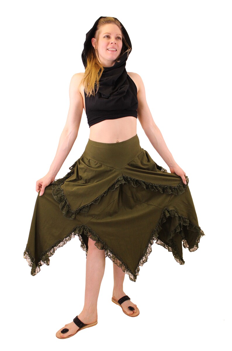 Puede incluir: Una falda verde con ribete de encaje negro y un top negro con capucha. La falda es asim&eacute;trica y tiene una cintura alta.