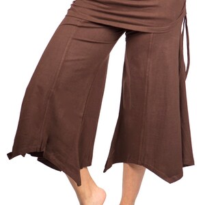 May include: Brown wide-leg pants with a draped skirt overlay and a tie at the side. The pants are made of a soft, flowing fabric.