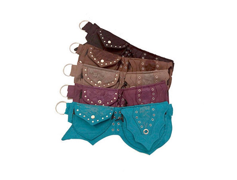 May include: A set of six colourful suede hip bags with decorative metal accents. Each bag has a flap with a snap closure and a small pocket on the front. The bags are arranged in a stack, with the top bag being turquoise, followed by burgundy, brown, tan, and two brown bags.