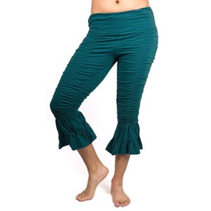 May include: Teal blue cropped pants with a ruffled hem. The pants are made of a soft, stretchy fabric and have a comfortable fit.