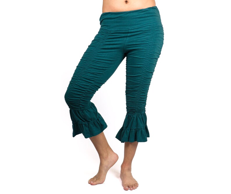 May include: Teal blue cropped pants with a ruffled hem. The pants are made of a soft, stretchy fabric and have a comfortable fit.