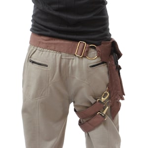 Puede incluir: Un cintur&oacute;n de cuero marr&oacute;n con una hebilla de metal y una correa de pierna de cuero marr&oacute;n con hebillas de metal. El cintur&oacute;n se lleva sobre un pantal&oacute;n beige.