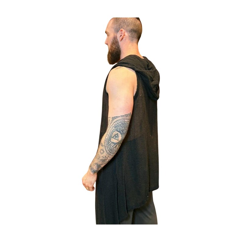 May include: A sleeveless black hooded vest with a long, flowing design. The vest is made of a soft, dark fabric. The person in the image has a full beard and a tattoo on their arm.