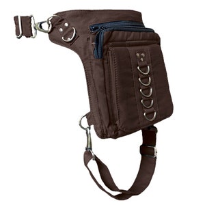May include: A brown canvas thigh bag with multiple pockets and a strap that goes around the leg. The bag has silver metal accents and a zipper closure.