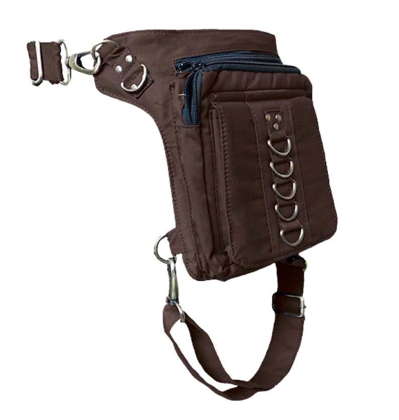 May include: A brown canvas thigh bag with multiple pockets and a strap that goes around the leg. The bag has silver metal accents and a zipper closure.