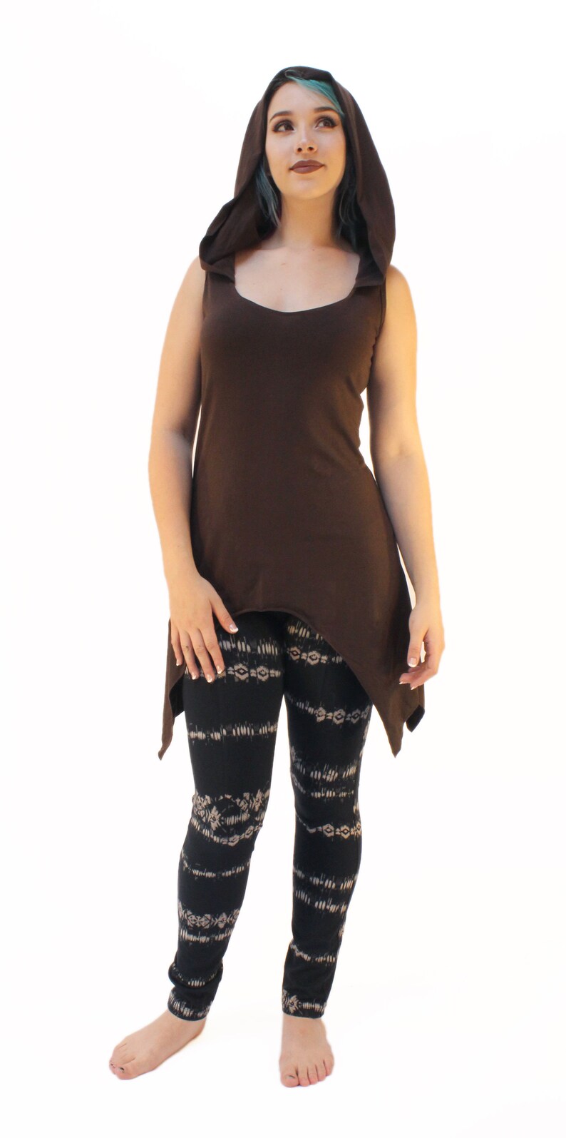 May include: A brown sleeveless top with a hood and a high low hemline. The model is wearing black and white patterned leggings.