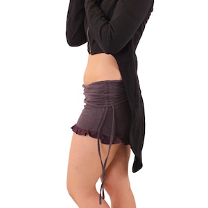 May include: A black hooded jacket with a long tail, worn with a dark grey skirt and silver sandals.