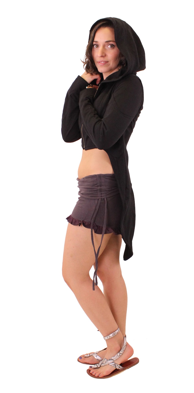 May include: A black hooded jacket with a long tail, worn with a dark grey skirt and silver sandals.
