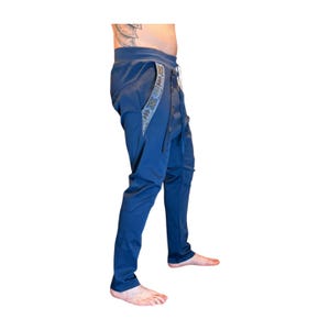 Puede incluir: Pantalones azul marino con cintura con cord&oacute;n y cierre de bot&oacute;n. Los pantalones presentan una franja decorativa estampada a lo largo del bolsillo. Los pantalones son de corte ajustado y de estilo casual.