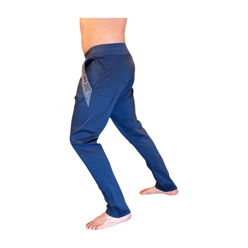 Puede incluir: Pantalones deportivos azul marino con un patr&oacute;n geom&eacute;trico decorativo en el lateral. Los pantalones tienen un dise&ntilde;o de pierna recta y una cintura con cord&oacute;n. La tela parece ser un material ligero y transpirable, adecuado para entrenamientos o uso casual.