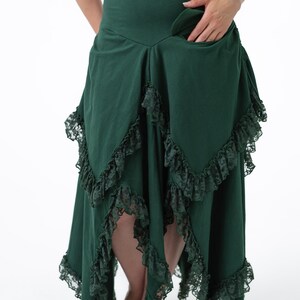 Puede incluir: Una falda verde oscuro con cintura alta y un dobladillo con volantes. La falda tiene un ribete de encaje y un bolsillo en el lateral.