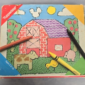 Könnte beinhalten: Ein Vintage-Malbuch von Tupperware Toys mit einer Farm-Szene. Das Buch zeigt einen roten Stall, eine Kuh, ein Schwein, ein Huhn und ein gelbes Küken. Das Buch enthält rote, gelbe und schwarze Buntstifte. Das Buch ist für Kinder ab 5 Jahren geeignet.