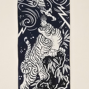 Puede incluir: Un tapiz de pared en blanco y negro con un diseño de tigre y dragón. El tigre está rayado y posicionado debajo de un dragón. La obra de arte incluye elementos de bambú y relámpagos.