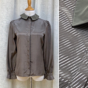 May include: A brown satin blouse with a white peter pan collar and long sleeves. The blouse has a subtle diagonal stripe pattern.