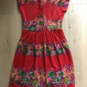 May include: A red dress with a floral print. The dress has a V-neckline and short sleeves. The skirt is gathered at the waist.