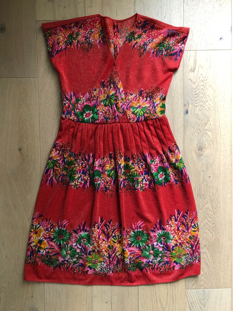 May include: A red dress with a floral print. The dress has a V-neckline and short sleeves. The skirt is gathered at the waist.