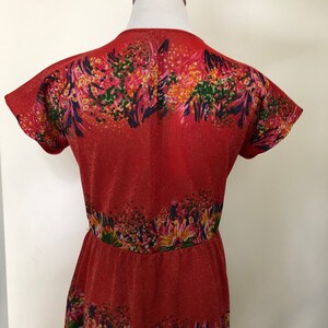 May include: A red dress with a floral print. The dress has a V-neckline and short sleeves. The fabric is a sparkly, textured material.