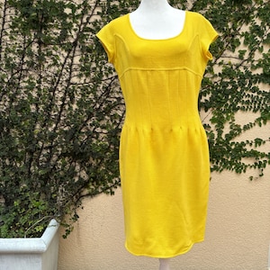 May include: A bright yellow sleeveless dress with a scoop neck and a fitted silhouette. The dress is made of a soft, knit fabric and has a subtle texture.