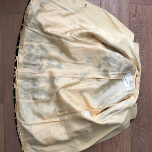 May include: The inside of a yellow and black leopard print blazer. The lining is a pale yellow color.