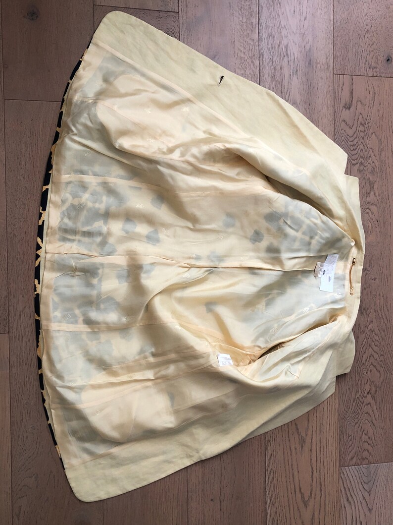 May include: The inside of a yellow and black leopard print blazer. The lining is a pale yellow color.