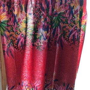 May include: Red sheer fabric with a floral print. The fabric has a shimmery finish and features a variety of colors, including pink, yellow, green, and blue.