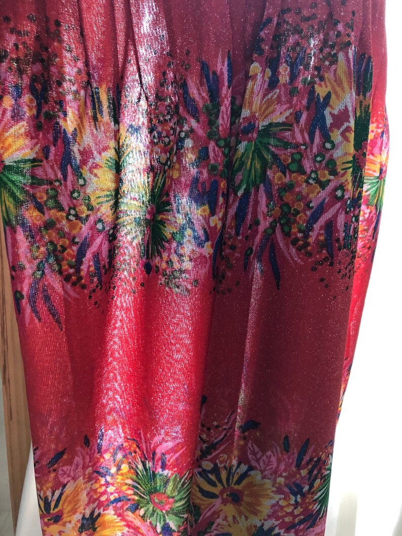 May include: Red sheer fabric with a floral print. The fabric has a shimmery finish and features a variety of colors, including pink, yellow, green, and blue.