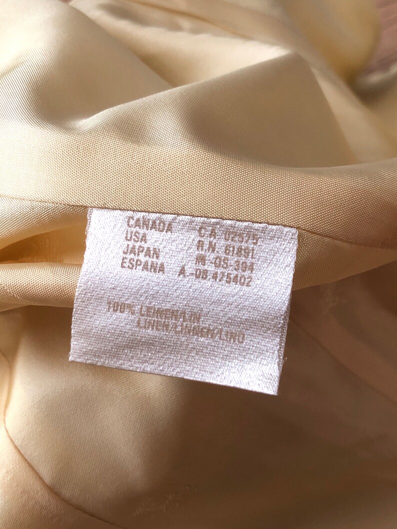May include: A white fabric care label with the text "CANADA CA 02575 R.N. 61891 USA JAPAN ESPANA A-08.475402 100% LEINEN/LINEN/LINO" printed on it.