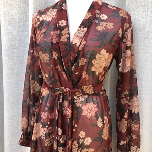 K&ouml;nnte beinhalten: Ein lang&auml;rmeliges, durchsichtiges, burgunderfarbenes Kleid mit Blumendruck, V-Ausschnitt und Bindeg&uuml;rtel.