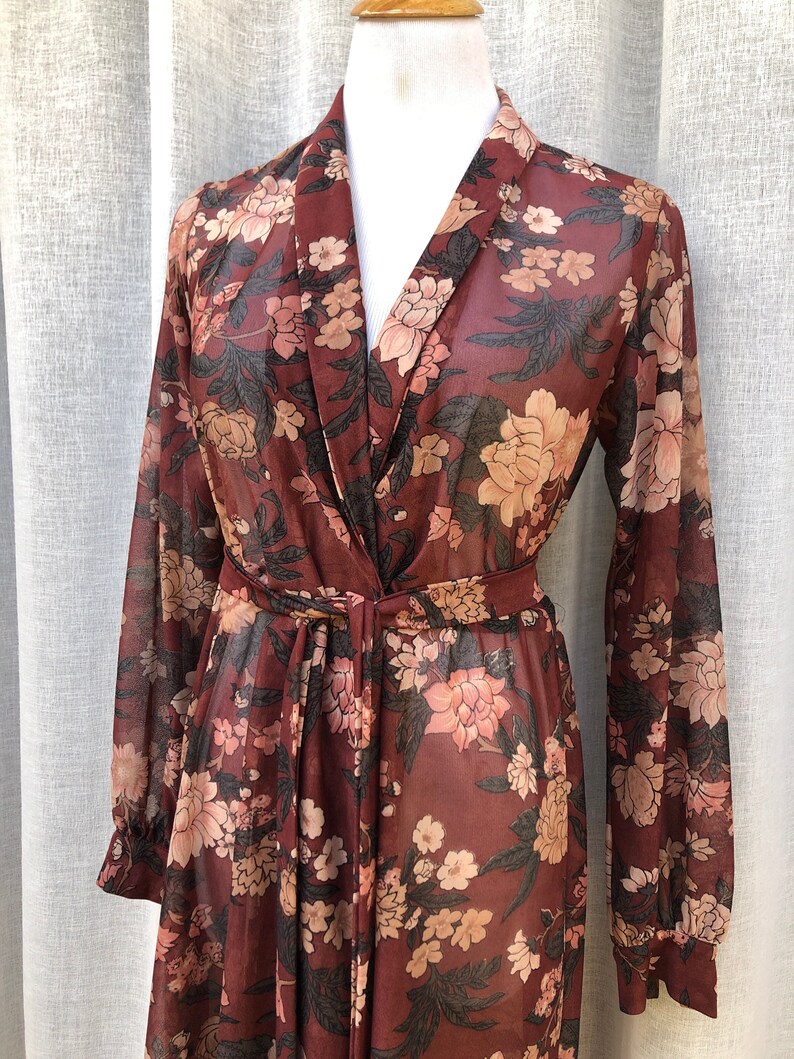 K&ouml;nnte beinhalten: Ein lang&auml;rmeliges, durchsichtiges, burgunderfarbenes Kleid mit Blumendruck, V-Ausschnitt und Bindeg&uuml;rtel.