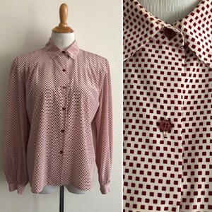 May include: A long-sleeved button-down shirt with a white background and a red geometric pattern. The shirt has a classic collar and long sleeves with button cuffs.