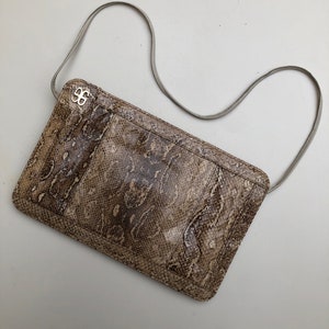 May include: A brown snakeskin clutch purse with a silver clasp and a light gray shoulder strap.