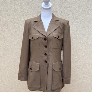 May include: A brown and white checkered blazer with a button-up front and two large flap pockets on the front. The blazer has a collar and long sleeves.