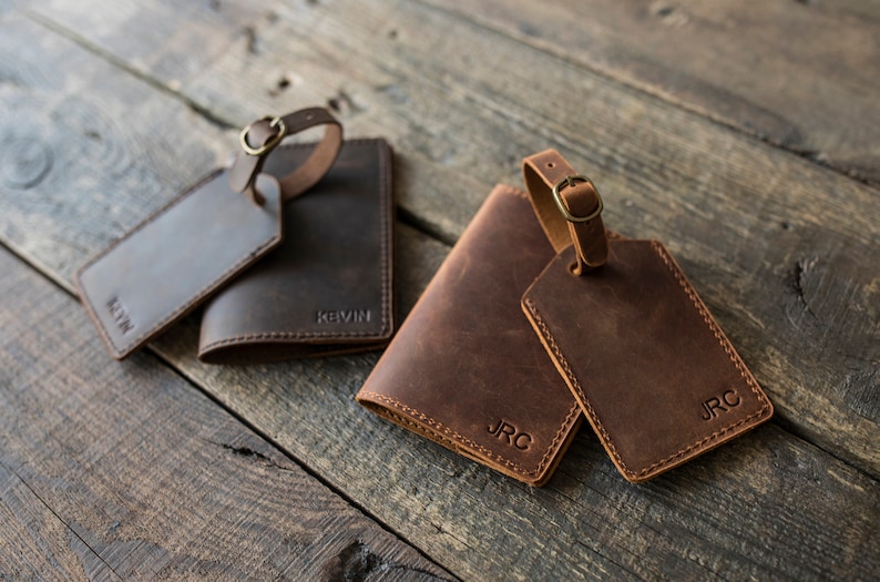 May include: Two brown leather luggage tags with the initials "JRC" and a brown leather passport holder with the initials "JRC".  A second brown leather passport holder with the name "Kevin" is also shown.