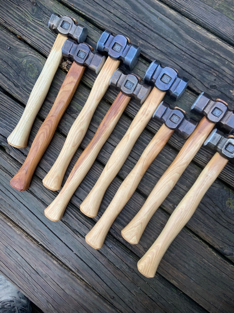 May include: A set of ten  hammer heads with wooden handles. The hammer heads are made of metal and have a polished finish. The handles are made of wood and have a natural finish.