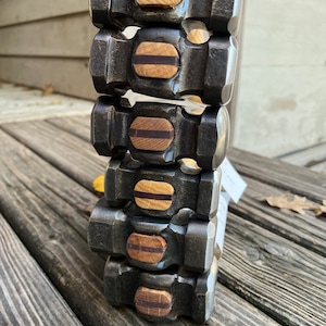 May include: A stack of six black metal hammers with wooden handles. Each hammer has a brown and black wooden inlay on the top.