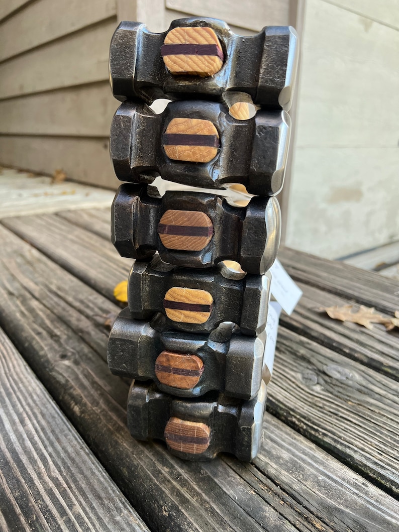 May include: A stack of six black metal hammers with wooden handles. Each hammer has a brown and black wooden inlay on the top.