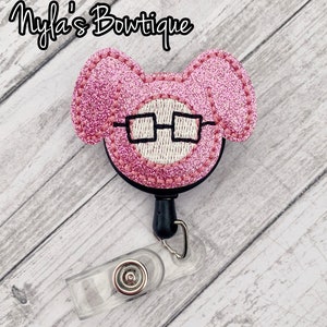 May include: Pink glitter mouse with black glasses, attached to a black retractable badge reel with a clear plastic badge holder.