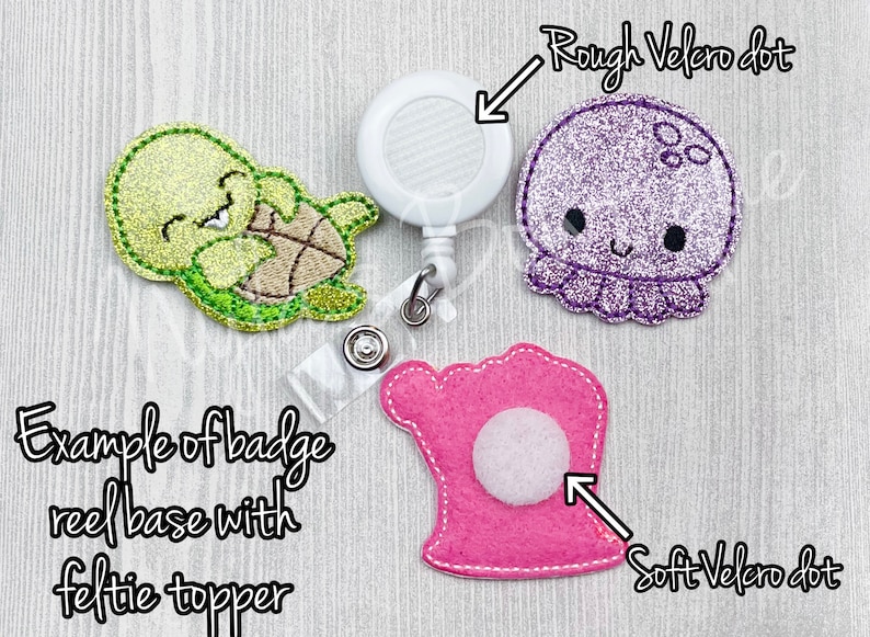 May include: Example of a badge reel base with a felt turtle topper. The reel has a white plastic base with a rough velcro dot. The turtle is green and yellow with a white face and black eyes. The felt topper is attached to the reel with a soft velcro dot.