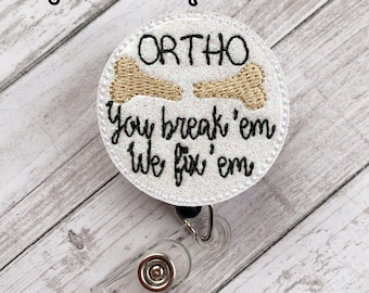 May include: White glitter badge reel with a white circle featuring a gold bone and the text "ORTHO You break 'em We fix 'em".