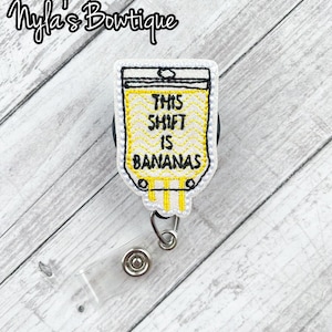May include: A yellow and white embroidered badge with a IV bag design and the text "This Shift Is Bananas". The badge is attached to a clear retractable badge reel.