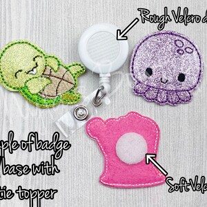 K&ouml;nnte beinhalten: Beispiel f&uuml;r eine Badge-Rollenbasis mit einem Filz-Schildkr&ouml;ten-Topper. Die Rolle hat eine wei&szlig;e Plastikbasis mit einem rauen Klettverschluss-Punkt. Die Schildkr&ouml;te ist gr&uuml;n und gelb mit einem wei&szlig;en Gesicht und schwarzen Augen. Der Filz-Topper wird mit einem weichen Klettverschluss-Punkt an der Rolle befestigt.
