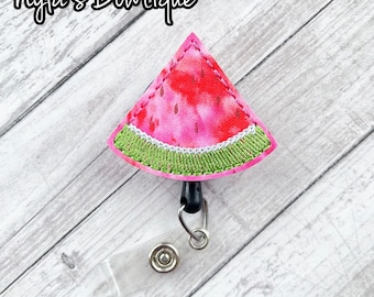 May include: A pink and green watermelon-shaped fabric badge holder with a clear plastic retractable badge reel.