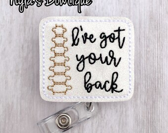 May include: White glitter badge holder with a black embroidered spine and the text "I've got your back". The badge holder has a clear plastic clip.