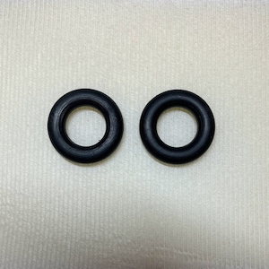 May include: Two black rubber o-rings, each with a circular shape and a hole in the center.